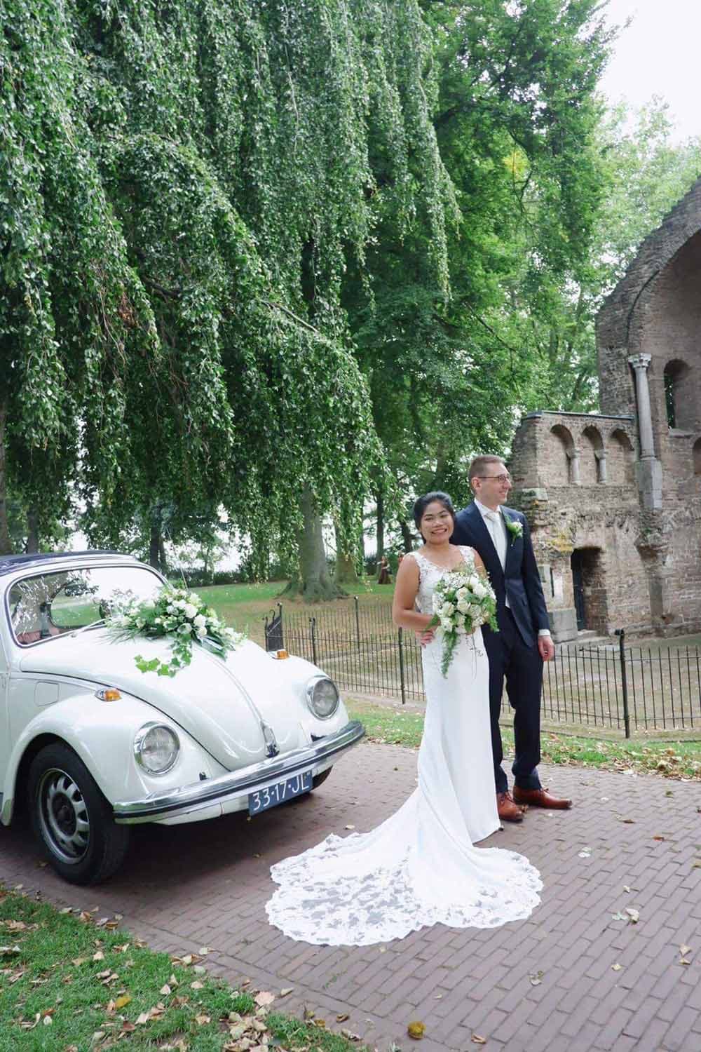 Nauwsluitende elegante trouwjurk met kant en lange sleep van kant.